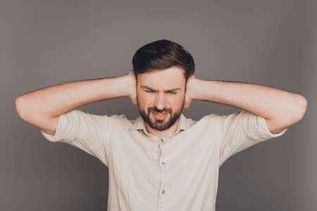 Sad overworked man with headache covering ears from noiseの写真素材