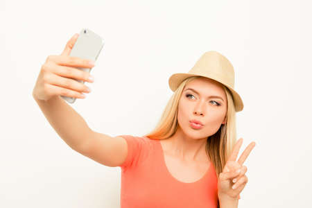 Woman in hat making selfie, pouting  and showing two fingersの写真素材