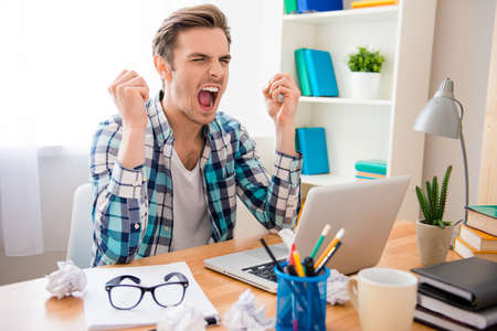 Frustrated young man working with laptop and screamingの写真素材