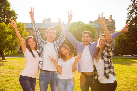 five cheerful best friends having fun  and rise hands  with gesture v-signの写真素材