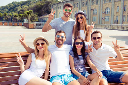 Six happy successful young people having fun and showing v-sign gestureの写真素材