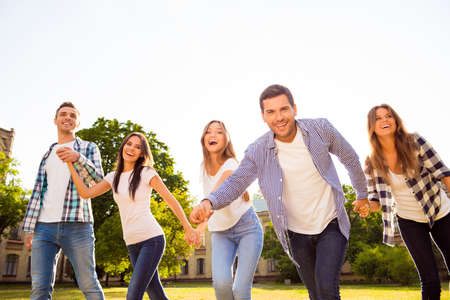 five cheerful best friends holding hands and having fun