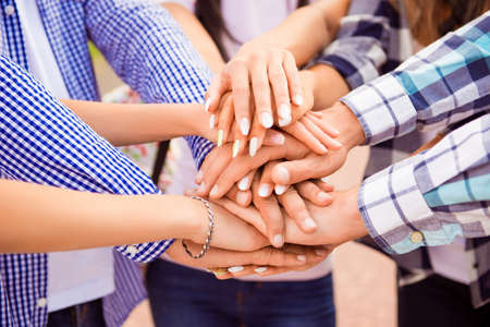 close-up photo of young friends putting their hands on top of each other. They achievement harmony in teamの写真素材