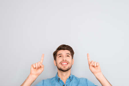 Handsome man gesturing with fingers under head on gray backgroundの写真素材