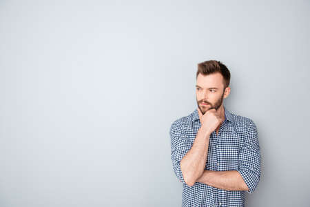 Concentrated thoughtful businessman touching chin on gray backgroundの写真素材