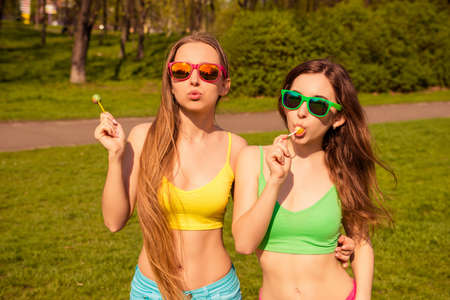 Portrait of two sexy girls in glasses licking lollipops