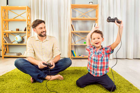 Father and  son playing video games. Son winningの写真素材