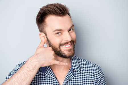 Portrait of cheerful smiling guy asking to call himの写真素材