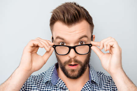 Portrait of shocked modern man touching his spectacles