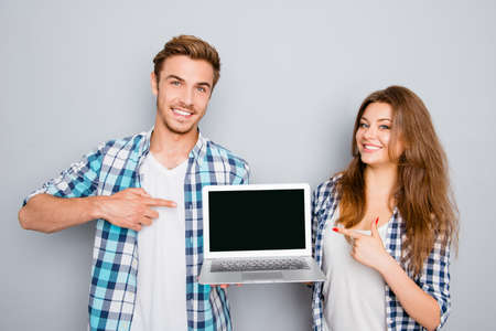 Young couple demonstrating laptop and pointing on screen with copyspaceの写真素材