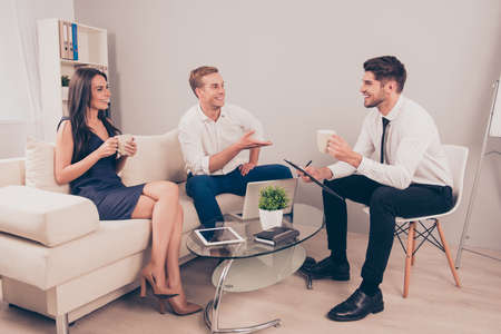 Young happy colleagues having free time and drinking coffeeの写真素材