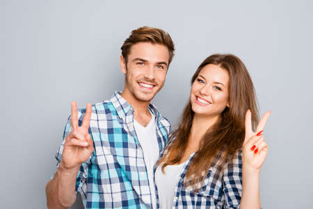 Cheerful happy young couple showing two fingersの写真素材