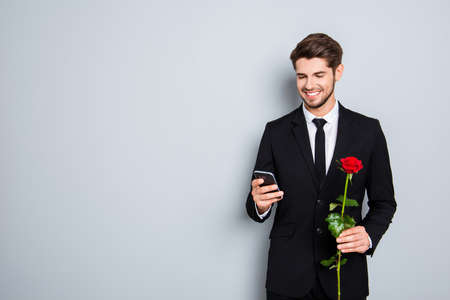 Cheerful smiling businessman with rose chatting on gray backgroundの写真素材
