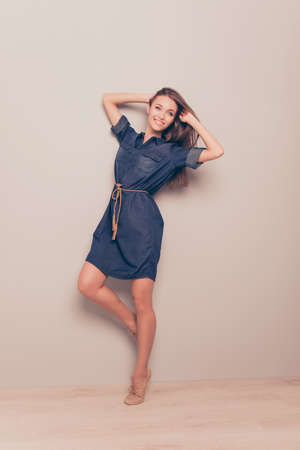 Playful pretty girl in jeans dress playing with hairの写真素材