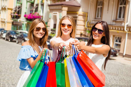 Three attractive girls in spectacles showing their purchasesの写真素材
