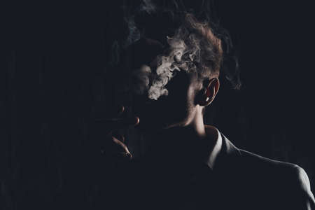Mystery man with cigar and smoke isolated on black backgroundの写真素材
