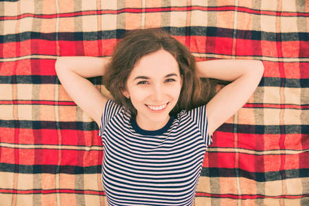 Top view of young smiling woman lying on plaid and relaxingの写真素材