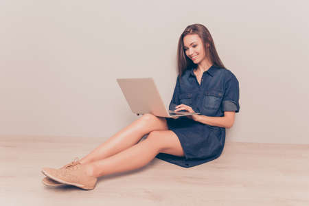 Smiling woman sitting on floor with laptop and doing her job onlineの写真素材