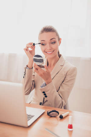 Attractive woman in office having break and doing maquillageの写真素材