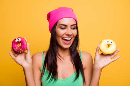 Portrait of happy hipster girl choosing beetwen two donutesの写真素材