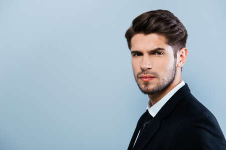 Portrait of serious young businessmman in suit on gray backgroundの写真素材
