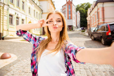 Selfie of funny attractive girl pouting and showing v-signの写真素材