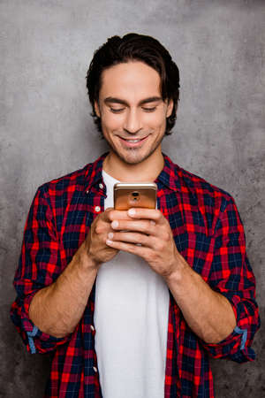 Portrait of happy man teping message on smartphone on gray backgroundの写真素材