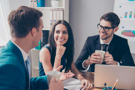 Cheerful office workers  discussing their project over cup of tea