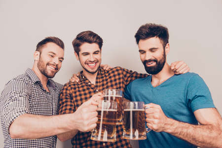 It is a goal! Three happy young men clinking with glasses of beerの写真素材