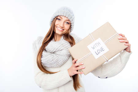 Cheerful woman  in warm hat and scarf holding package and congratulate with xmas