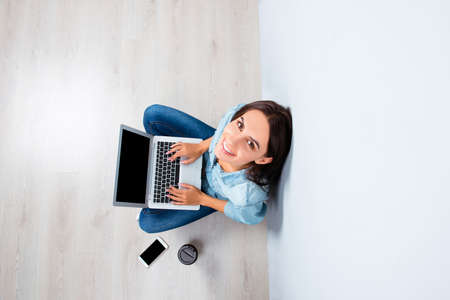 Pretty happy woman sitting on floor with laptop, top view photoの写真素材