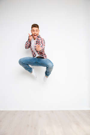 Happy young guy jumping and pointing on camera