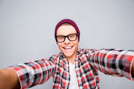 Selfie of young totthy hipster man in violet hat and glassesの写真素材