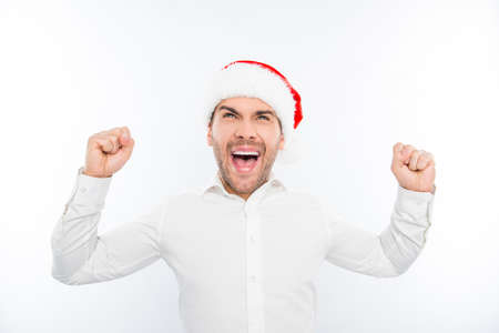 Excited happy man in santa's hat celebrating new year and triumphingの写真素材