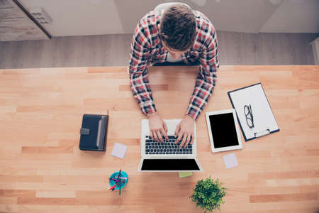 Top view of businessman doing paperwork and typing on laptop
