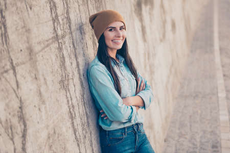 Cheerful happy young woman in hat with crossed handsの写真素材