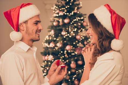 Young happy man making proposal of marriage his excited on x-mas evening while standing in profileの写真素材