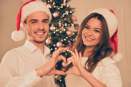Happy couple in love celebrating christmas and gesturing heart with fingers