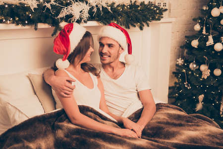 Handsome man huging his wife in bed on christmas holidaysの写真素材