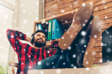 Young relaxed manager listening music on snowy backgroundの写真素材