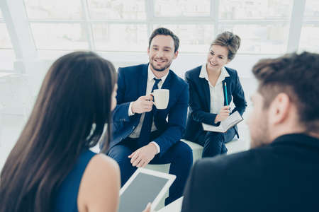 Happy colleagues drinking coffee while discussing new projectの写真素材