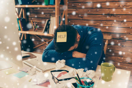 Tired sad man having long working day and needing help on snowy backgroundの写真素材