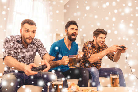 Excited  cheerful men play video game with beer on xmas holidaysの写真素材