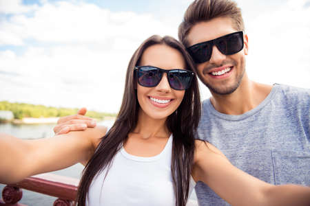 Selfie of happy cute lovers in glasses having walk in cityの写真素材