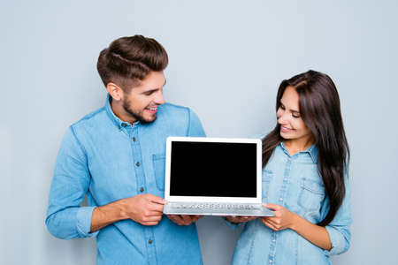 Happy man and woman showing black screen of modern laptopの写真素材