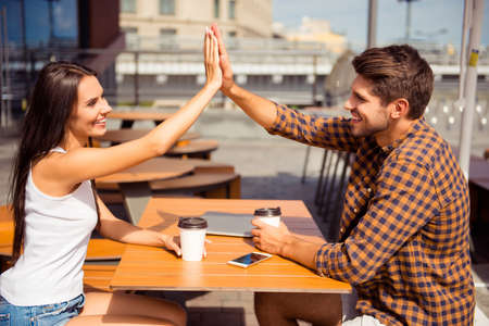 Happy pretty woman giving high five to her boyfriend in cafeの写真素材