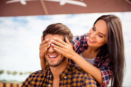 Young smiling woman closing eyes of her boyfriend in cafeの写真素材