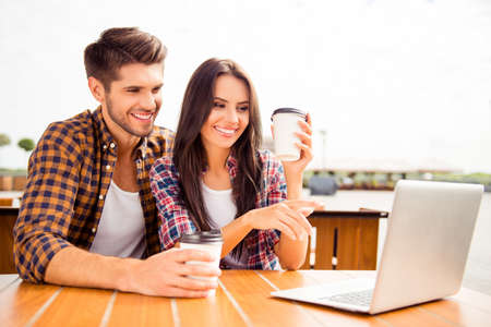 Beautiful happy young couple with laptop in cafe watching filmの写真素材