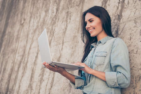 Smiling woman holding laptop and checking her emailの写真素材