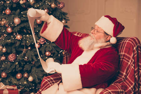 Portrait of Santa Claus reading roll of paper with  list of children's wish and presents